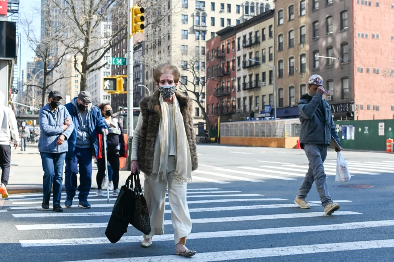 a woman with a white mask on her face walks across the street