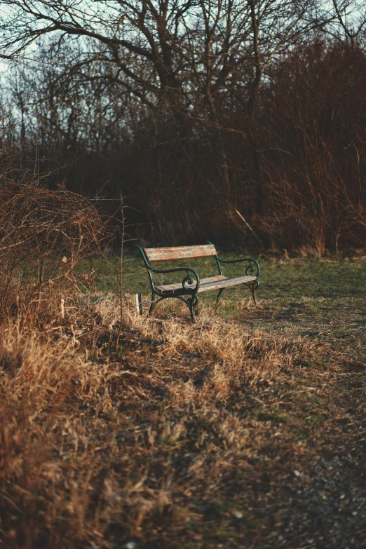 an empty park bench is next to the field