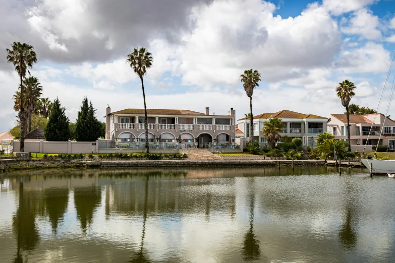 a large house on the water surrounded by palm trees