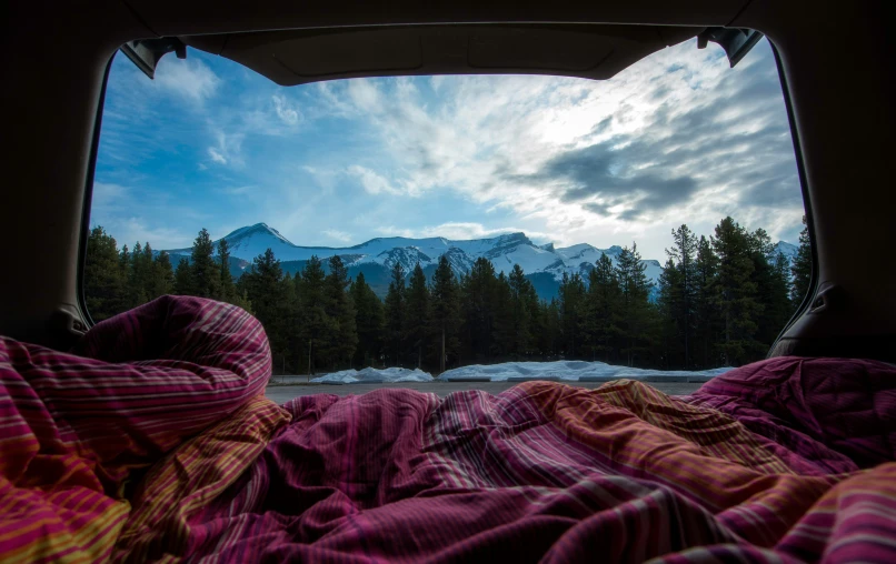 two people sleeping in a van with the sun shining down