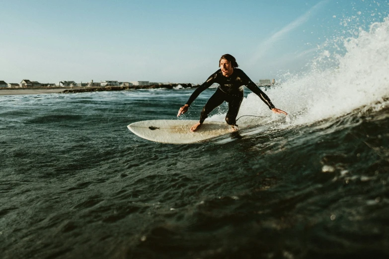 a woman in a wetsuit surfboarding on the ocean