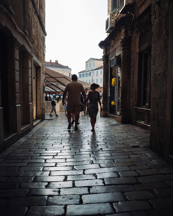 two people are walking on an alley between buildings