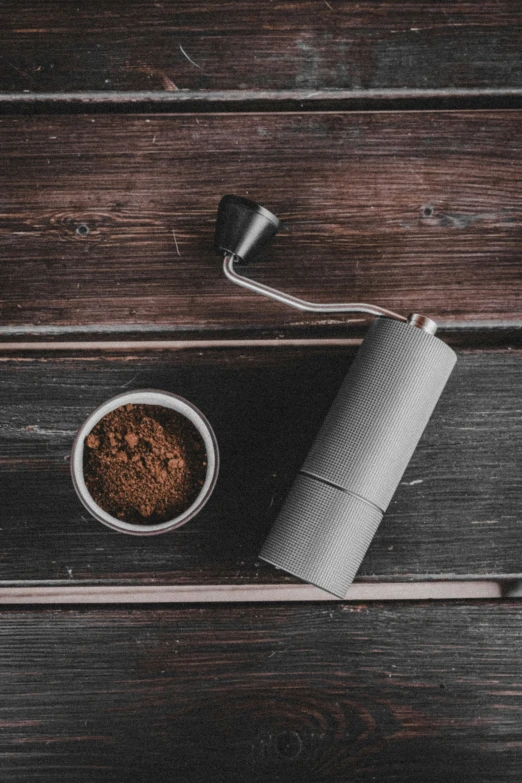 a couple of brown grinders next to a bowl of coffee grounds