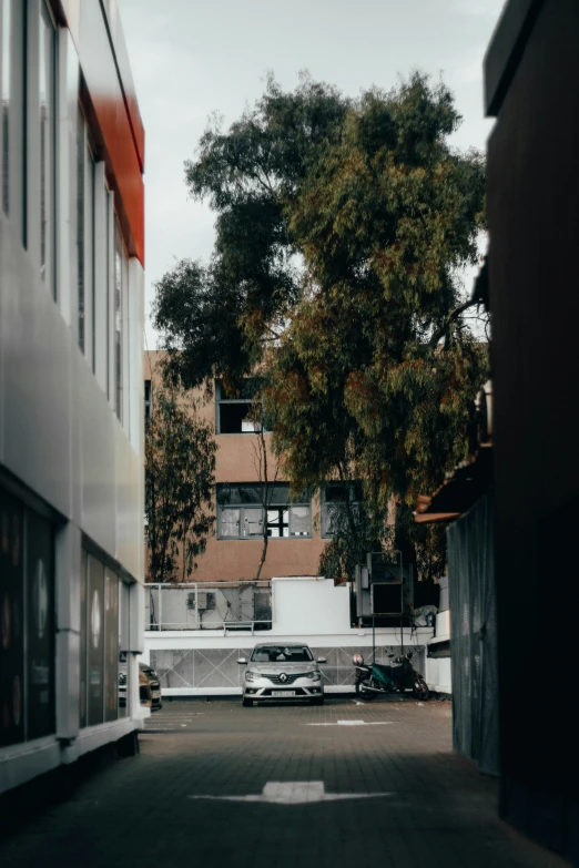 a long empty street between two buildings with a few cars parked out front