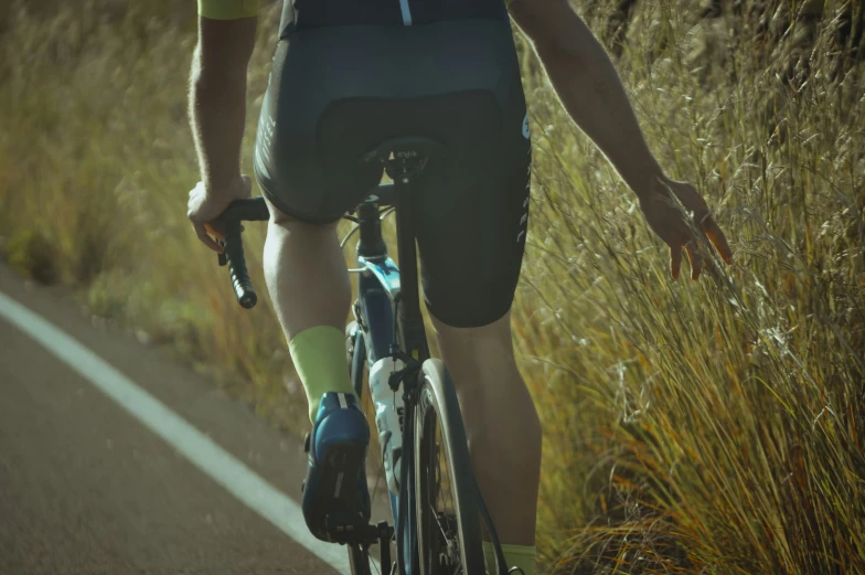 the legs and the arms of a biker riding their bicycle down the road