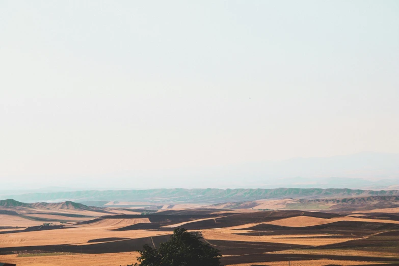 a plane flying in a cloudy sky over a rural landscape