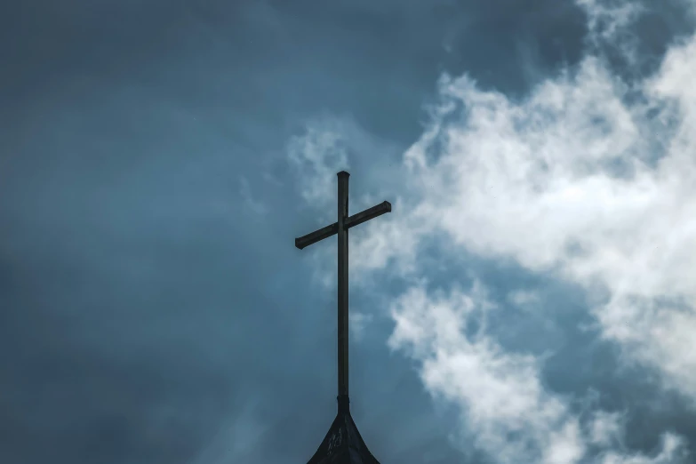 the cross is above the steeple in a dark sky