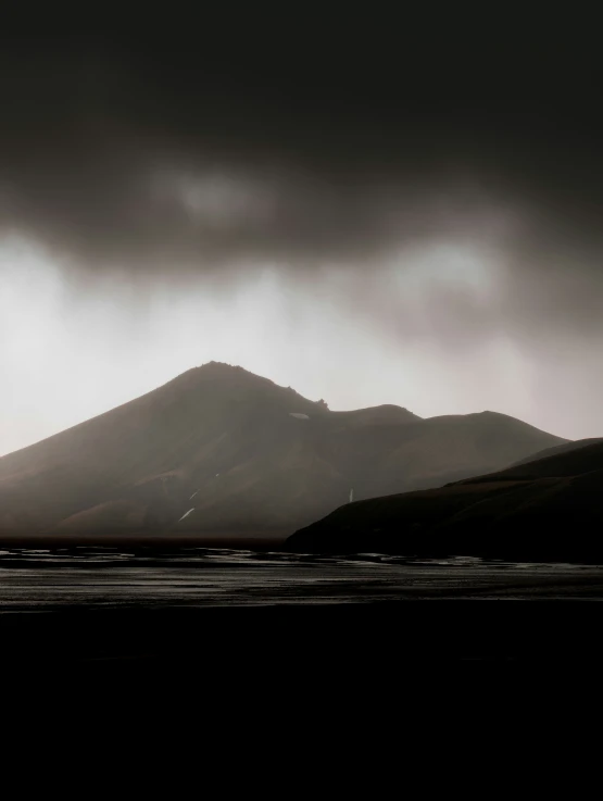 an airplane flying above a mountain covered in dark clouds