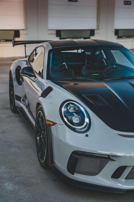 a black and white sports car is parked in front of two garage doors