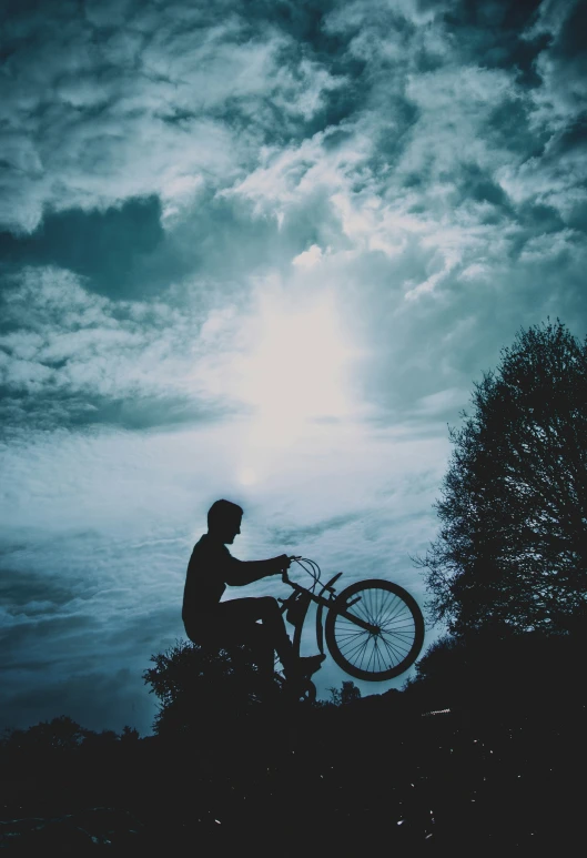 silhouette of a person on a bike against dark clouds