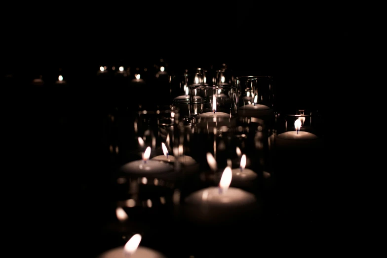 many lit candles glowing in a dark room