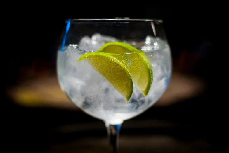 a glass that is filled with ice and some lemon wedges