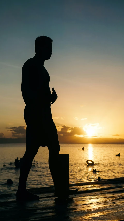 a silhouette of a man with a bucket and a hat by the water