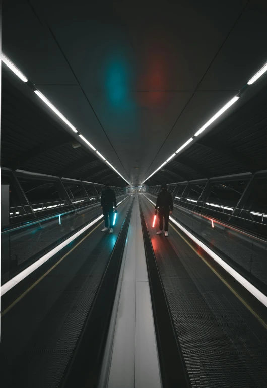 two people in a long tunnel with a bright green light