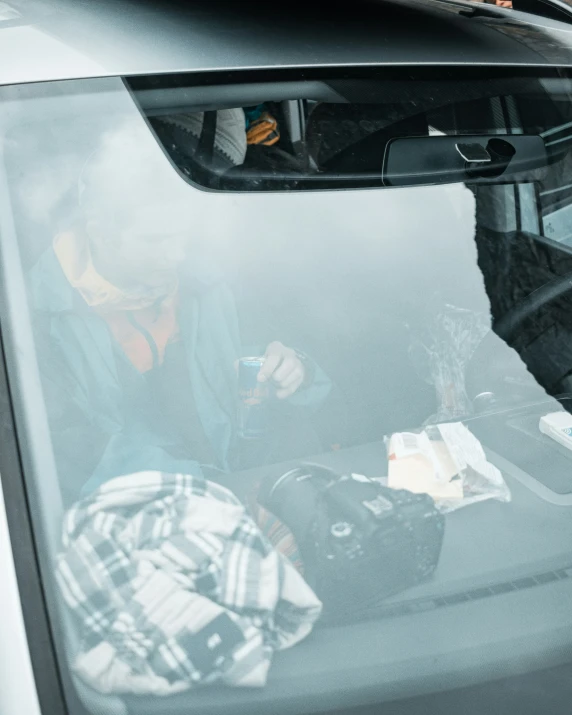 a man in plaid shirt sitting on his phone in the back of a car