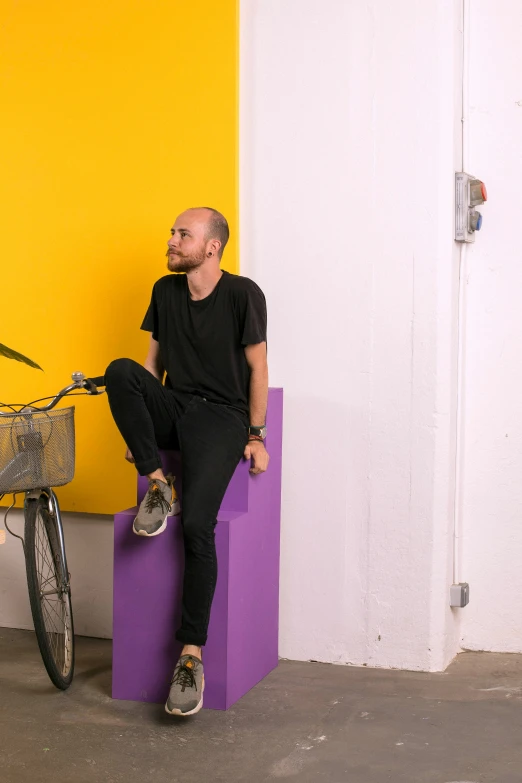 man sitting on the side of a building with a bike