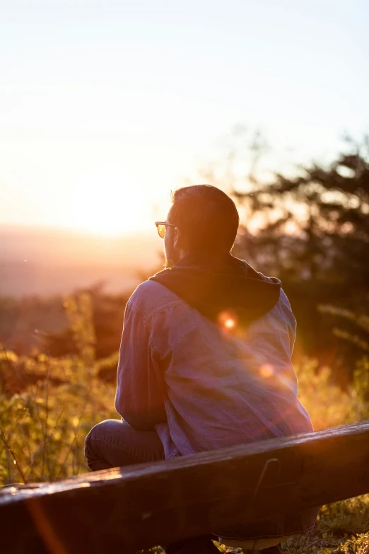 man sitting on a bench in the sunset