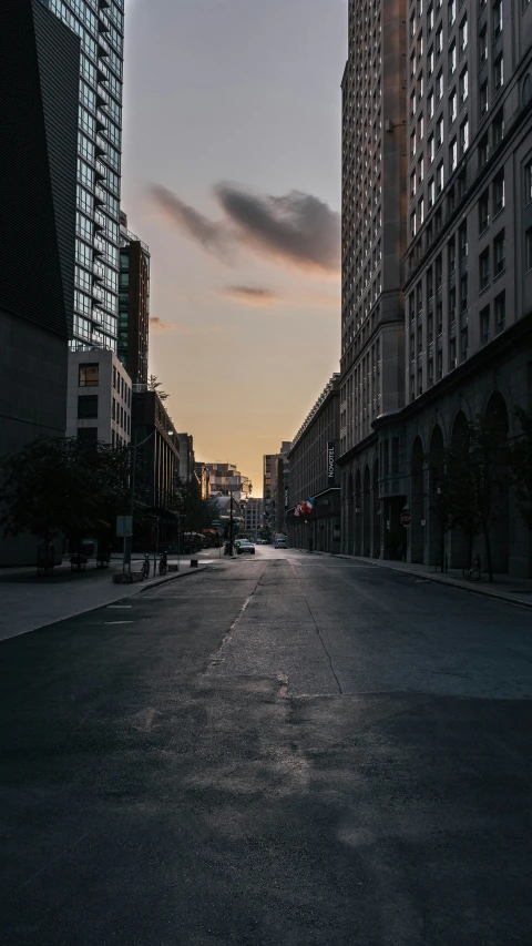 a wide city street at sunset with buildings in the background