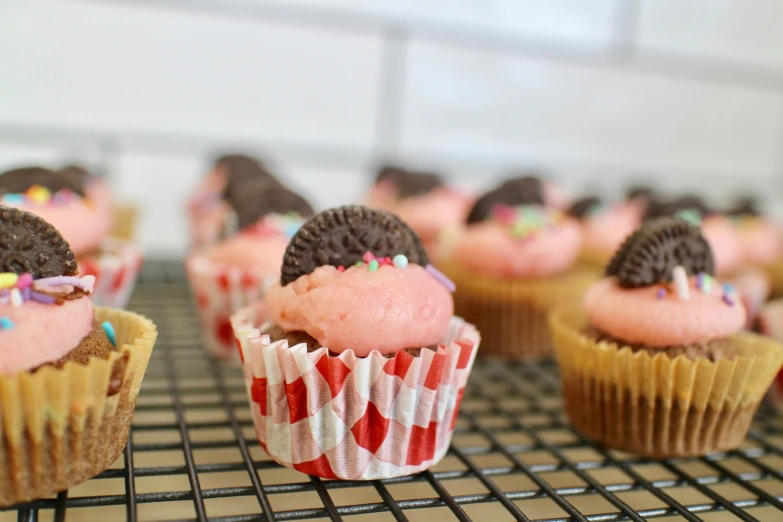 several cupcakes with different toppings sitting on top of a cooling rack