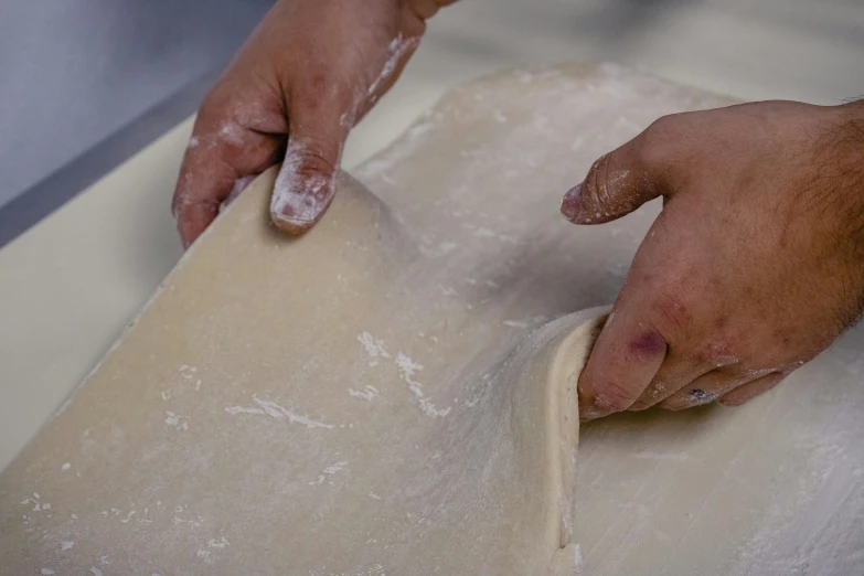 a person rolling out dough with their hands