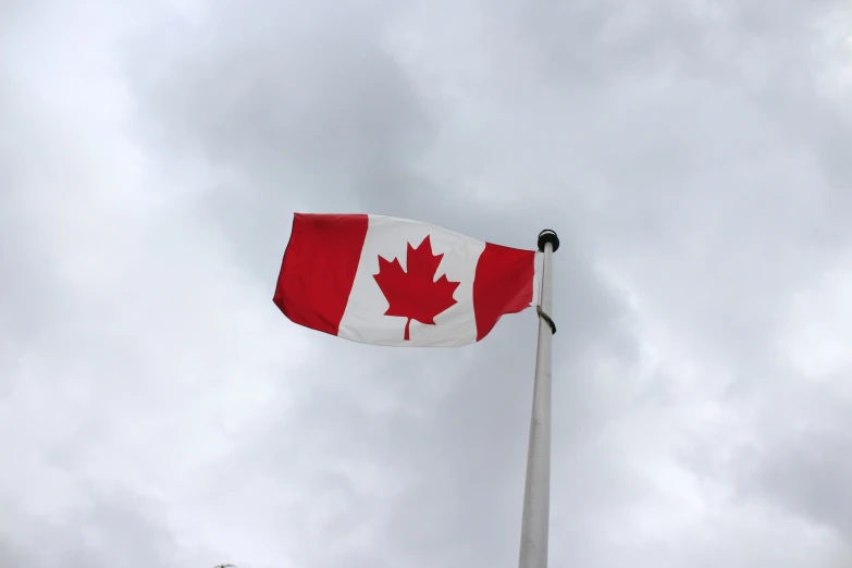 an canadian flag flying high on a cloudy day