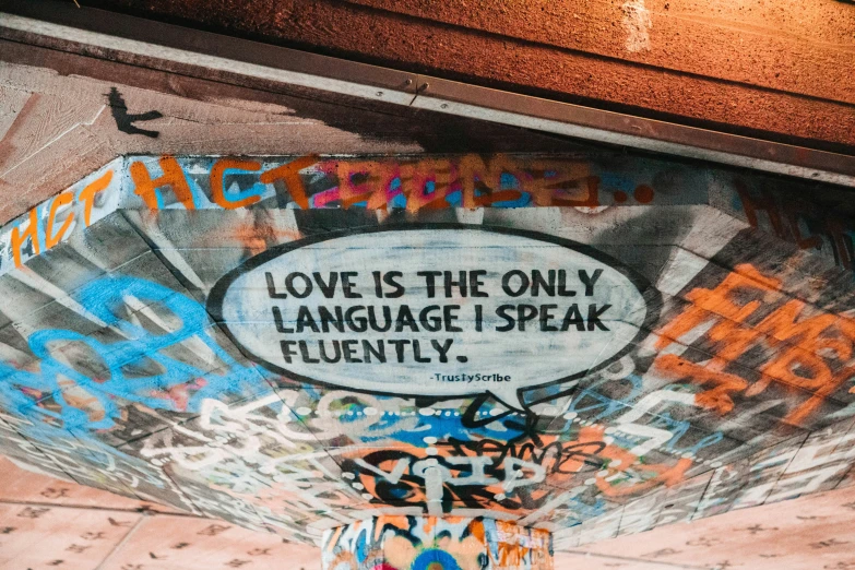 graffiti all over a wall with the words love is the only language i speak fluent