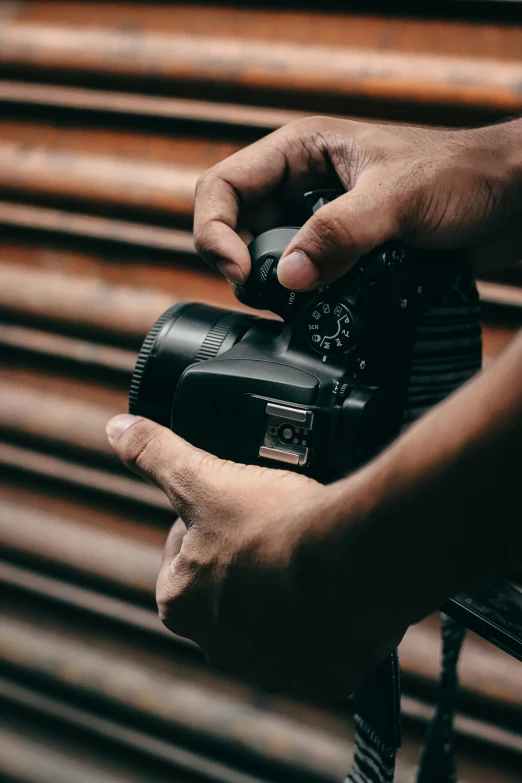 the man holds his camera with one hand and the other on top of the camera