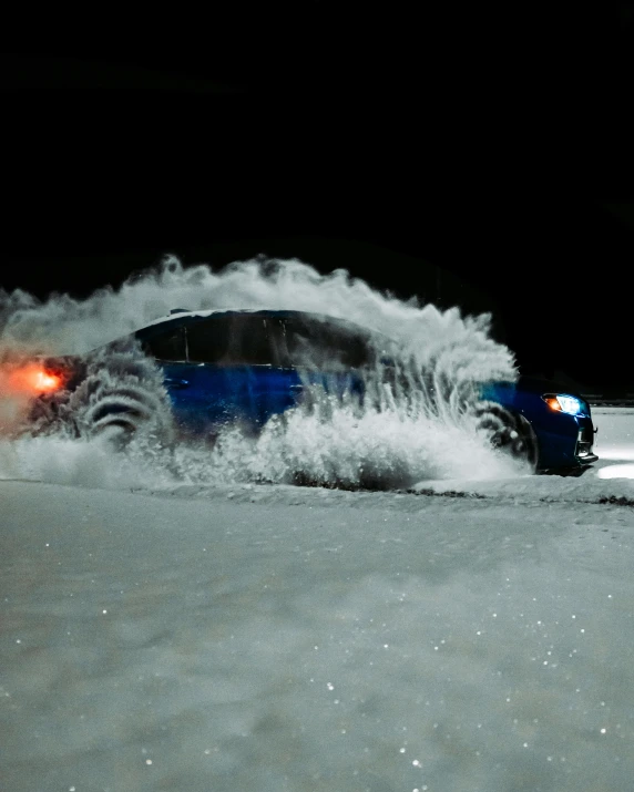 blue car drives through a snow drift on an icy night