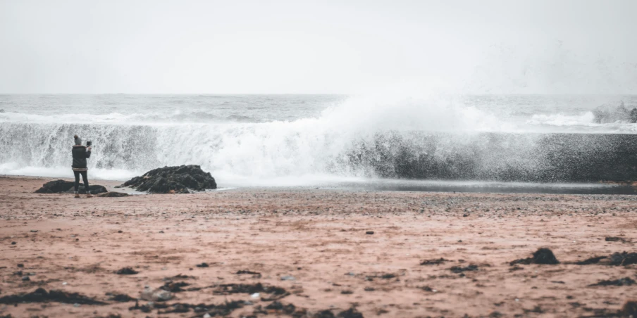 two people are standing on a beach by some waves