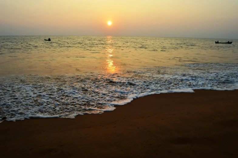 several boats in the ocean and one is at sunset