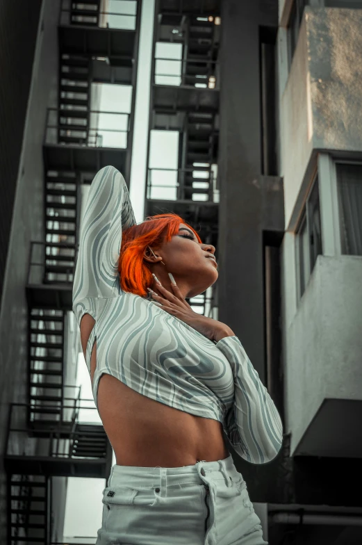 woman with red hair and wearing striped shirt standing in front of a building