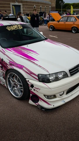 a white car has pink streaks painted on the hood