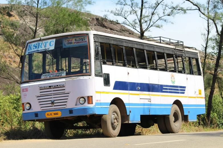 a bus parked next to a mountain covered with trees