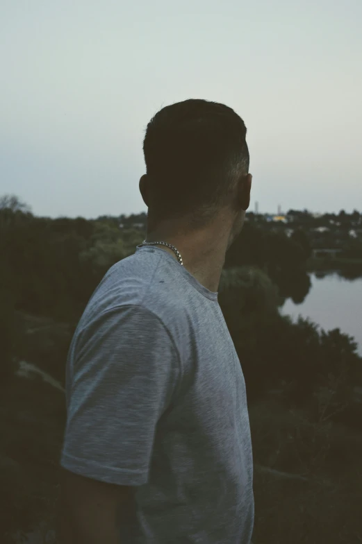 man wearing silver necklace standing on the edge of water