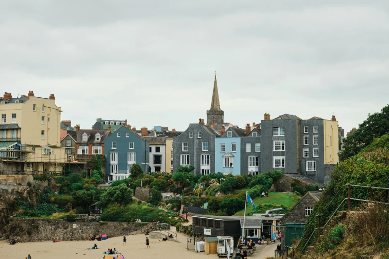 a beach with houses, a lighthouse and a hill