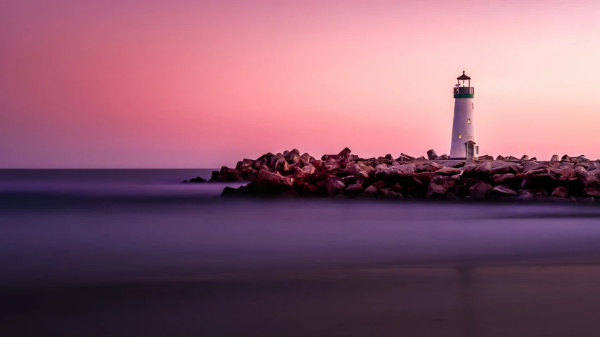 there is a white lighthouse at the beach at dusk