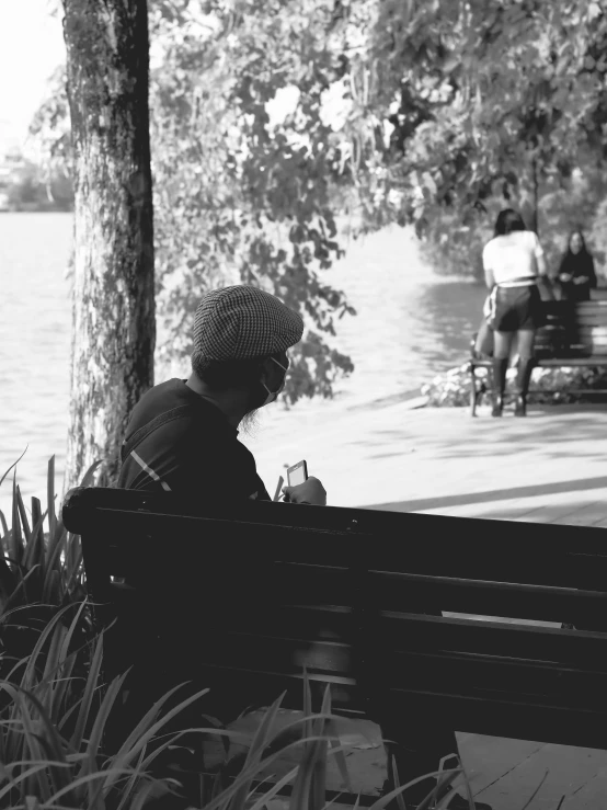 an elderly lady sitting alone in the park on a bench looking at her phone