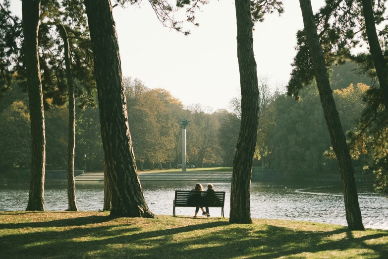 a couple sitting on a park bench by the lake