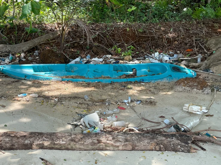 a blue boat in sand near a forest