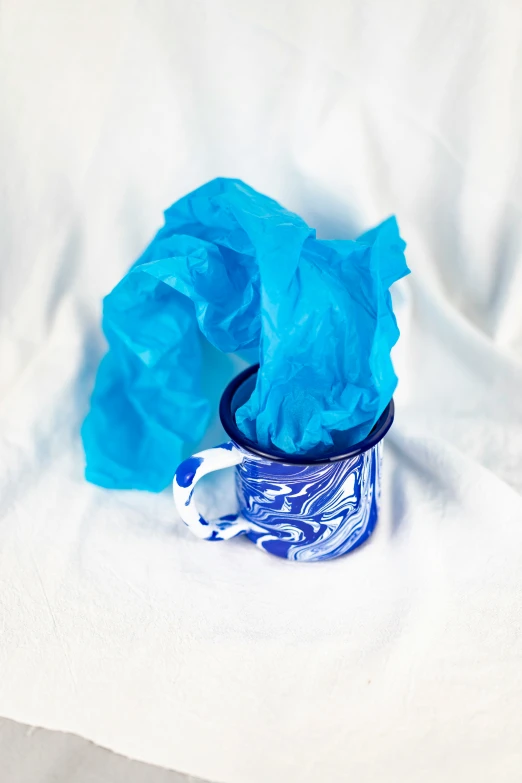 a blue and white napkin with a cup next to it