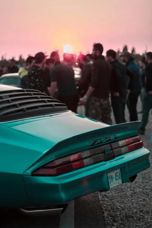 group of people walking by a parked car during sunset