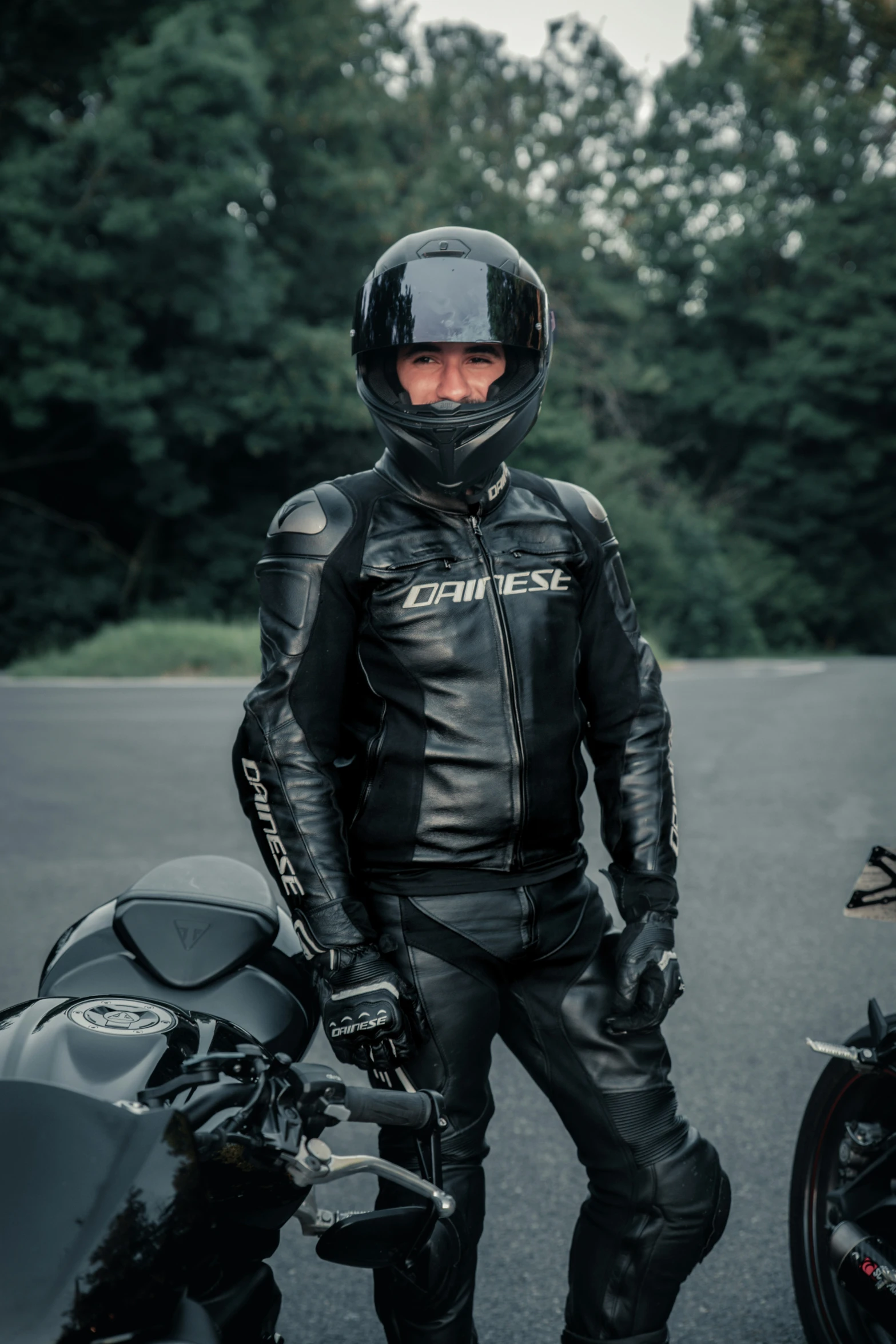 a motorcycle rider is standing next to his black motorcycle