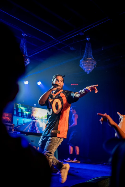 the young man in an orange shirt stands on stage