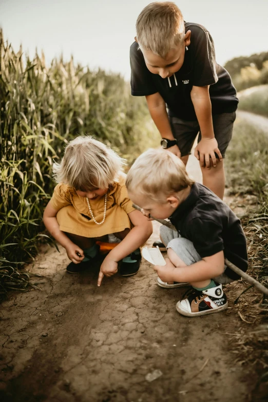 two boys are playing with a baby while two adults watch them