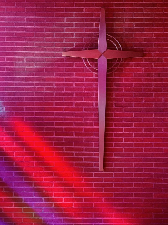 the cross on the brick wall is in front of a brick wall