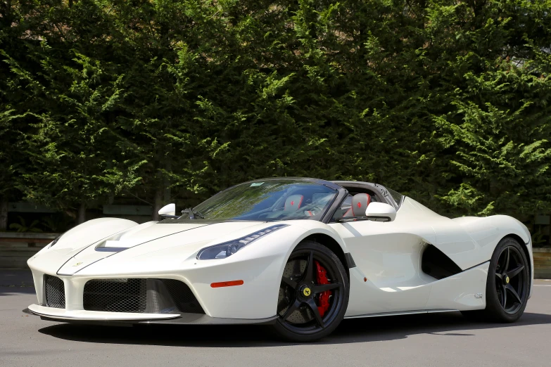 a white sports car is parked in front of some trees