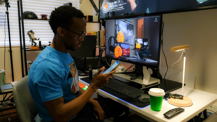 a man looks at his remote control in front of the computer screen