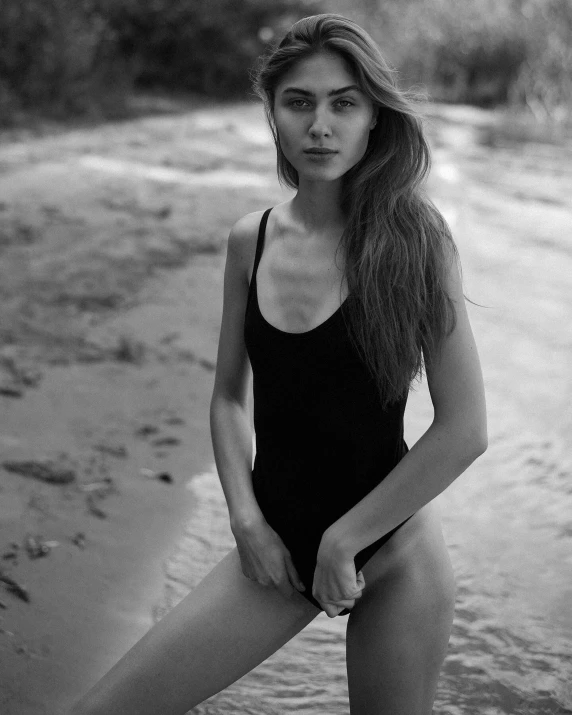 a woman in black bathingsuit posing on the beach