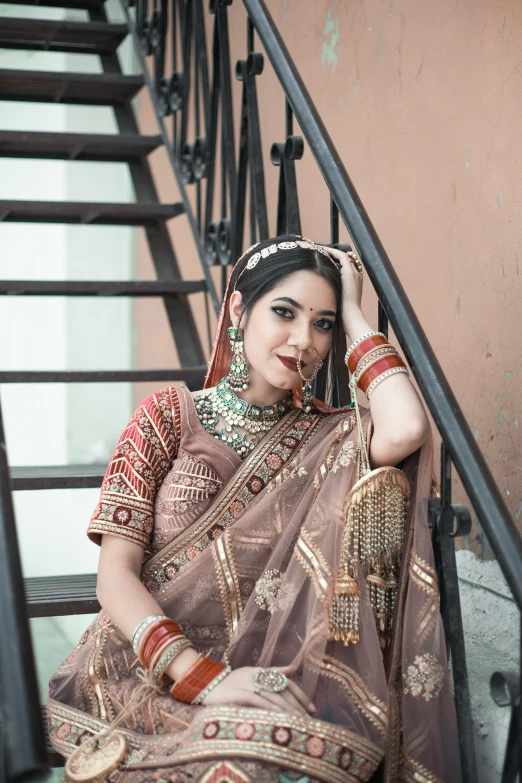 a woman in a traditional indian outfit sitting on the steps