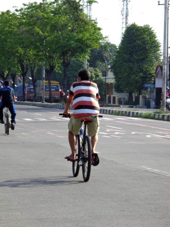 two people on bikes, one riding down a street while the other skateboards